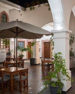 un patio con mesas y una sombrilla grande en Hotel Catedral en Cuernavaca