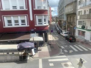 een vrouw die over een straat loopt met een paraplu bij Piso del Columpio II en CENTRO de Lugo in Lugo