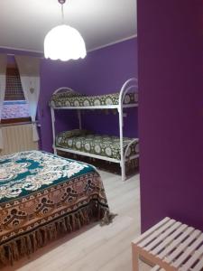 um quarto roxo com duas camas e um banco em La Casa di Romeo em Ateleta