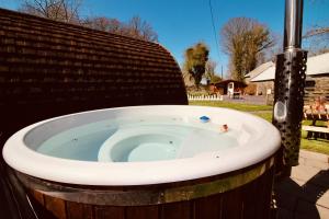 a jacuzzi tub in a yard with a fence at Dog Friendly Glamping Pods with Hot Tubs in Dwyran