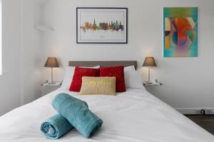 Una cama blanca con almohadas rojas y toallas azules. en Exeter City Centre Apartments Baxter Apartment en Exeter