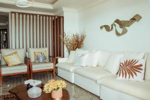 uma sala de estar com um sofá branco e duas cadeiras em Ed. Golden palace em Guarapari