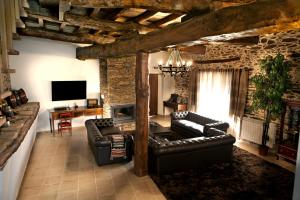 a living room with leather furniture and a stone wall at Casa do Médico in Carção