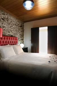a bedroom with a large bed with a red headboard at Casa do Médico in Carção +26 photos