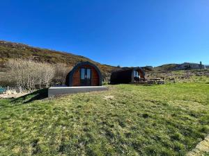 a small cabin in the middle of a grass field at Tighlochan pods in Scourie