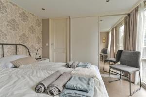 a white bedroom with two beds and a chair at Ruime Luxe Chalet midden in de Veluwe. in Hoenderloo