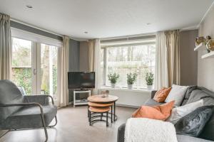 een woonkamer met een bank en een tv bij Ruime Luxe Chalet midden in de Veluwe. in Hoenderloo