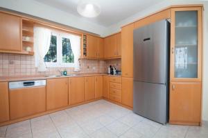 a kitchen with wooden cabinets and a stainless steel refrigerator at Villa Spyros in Nisaki