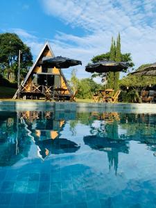 un complejo con una piscina de agua con mesas y sombrillas en Refúgio do Cerrado, en Anápolis