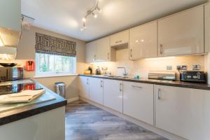 a kitchen with white cabinets and a counter top at Gleneagles Apartment - Guthrie Court Gleneagles in Auchterarder