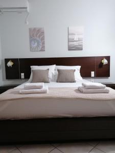 Lefakis Aegean Breeze Apartment في Órmos: سرير كبير بملاءات ووسائد بيضاء