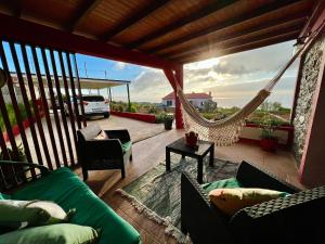 un porche con sofás y una hamaca en el balcón en Victoria Tiny Stone House en Ponta do Pargo