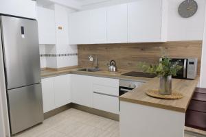 a kitchen with white cabinets and a stainless steel refrigerator at EDEN RENTALS Rincón Cozy in Taco