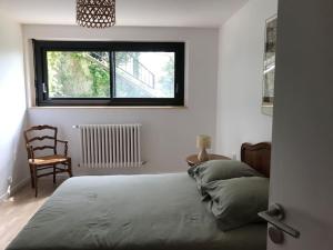 sypialnia z łóżkiem, krzesłem i oknem w obiekcie Maison Bertrand w mieście Saint-Marcellin