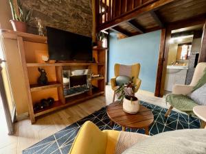 a living room with a couch and a tv at Victoria Tiny Stone House in Ponta do Pargo