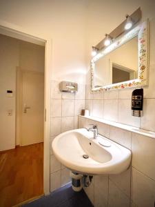 a bathroom with a white sink and a mirror at Pension Tokus in Nuremberg +57 photos