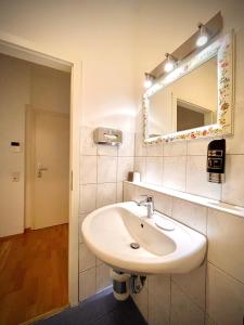 La salle de bains est pourvue d'un lavabo blanc et d'un miroir. dans l'établissement Pension Tokus, à Nuremberg