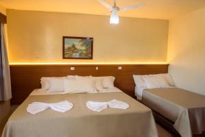 two beds in a room with white sheets and bows at Pousada dos Plátanos in Nova Petrópolis