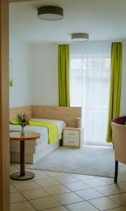 a bedroom with a bed with green curtains and a table at Pension Tokus in Nuremberg