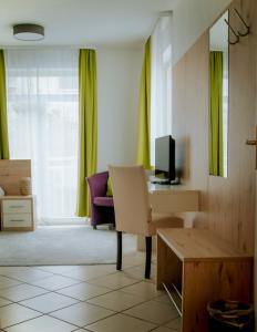 a living room with a chair and a desk with a television at Pension Tokus in Nuremberg