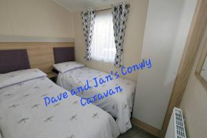 Dave and Jan's Conwy Caravan-Bryn Morfa في ديجانوي: غرفة نوم بسريرين ونافذة
