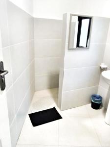 ein Badezimmer mit einer Dusche und einer schwarzen Matte auf dem Boden in der Unterkunft Savanna Tree Apartments - self catering town center in Livingstone