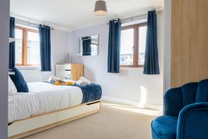 ein Schlafzimmer mit blauen Vorhängen sowie einem Bett und einem Stuhl in der Unterkunft Homely Two Bedroom Apartment in Milton Keynes - Free Parking, WiFi, Sky TV & Netflix in Milton Keynes