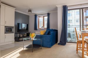 ein Wohnzimmer mit einem blauen Sofa und einem Tisch in der Unterkunft Homely Two Bedroom Apartment in Milton Keynes - Free Parking, WiFi, Sky TV & Netflix in Milton Keynes