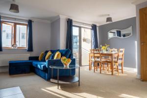 ein Wohnzimmer mit einem blauen Sofa und einem Tisch in der Unterkunft Homely Two Bedroom Apartment in Milton Keynes - Free Parking, WiFi, Sky TV & Netflix in Milton Keynes
