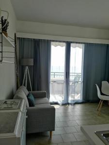 Una sala de estar con un sofá y una ventana grande. en Glyfada New Era Home 31 Menigos Resort Apartments, en Glyfada