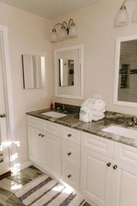 a white bathroom with two sinks and a mirror at Cabin with Treehouse Views, 3 King Beds, 4 Bunks, and Large Hot Tub! in Gatlinburg