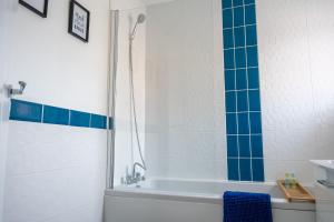 bagno con vasca e doccia con piastrelle blu di Four Bedroom, Four Bathroom Home in Milton Keynes by HP Accommodation a Milton Keynes