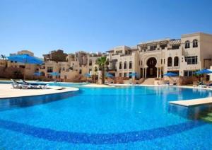 uma grande piscina com água azul em frente aos edifícios em Apartment Azzura Sahl Hasheesh with private garden em Hurghada