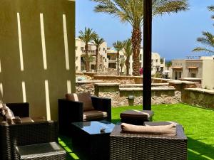 um pátio com cadeiras de vime, uma mesa e relva em Apartment Azzura Sahl Hasheesh with private garden em Hurghada