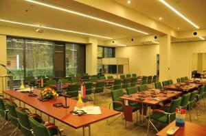 sala konferencyjna z długimi stołami i zielonymi krzesłami w obiekcie Ośrodek Wypoczynkowy Wielki Błękit w Łukęcinie