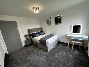 a bedroom with a bed and a desk and a tv at Two bed apartment with balcony Slough,Windsor,Legoland in Slough +25 photos