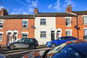 two cars parked in front of a brick building at Two Bedroom Home in Northampton by HP Accommodation - Free Parking & WiFi in Northampton