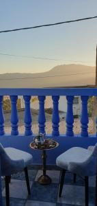 IDGA appartement with panoramic view في شفشاون: طاولة زرقاء مع كرسيين ووعاء على طاولة