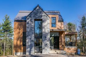 a house in the woods with glass windows at Allen Falls, chalet avec spa in Morin Heights