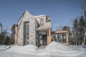 ein Haus im Schnee mit Schnee in der Unterkunft Allen Falls, chalet avec spa in Morin Heights