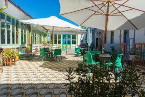 un patio al aire libre con mesas, sillas y sombrillas en Bichon La Casa Hostal, en Pichilemu