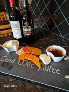 a cutting board with food and two bottles of wine at Dairy Cottage in Swordale