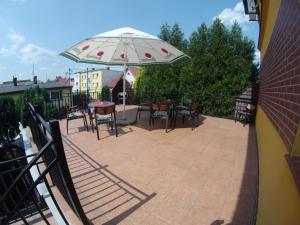 a patio with tables and chairs and an umbrella at Pasja Noclegi B&B in Wołów