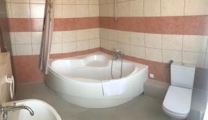 a bathroom with a white tub and a toilet at Pasja Noclegi B&B in Wołów