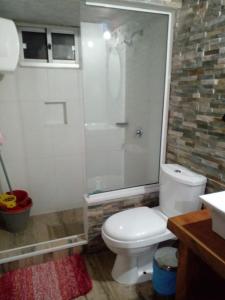 y baño con aseo blanco y ducha. en Cabañas Punta Palmar (Casa 3) en Punta del Diablo