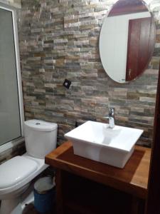 a bathroom with a sink and a toilet and a mirror at Cabañas Punta Palmar (Casa 3) in Punta Del Diablo