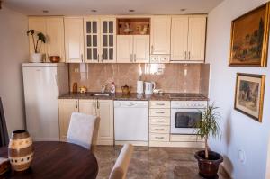 una cucina con armadi bianchi e tavolo in legno di Petrov konak - apartman Aleksandra 