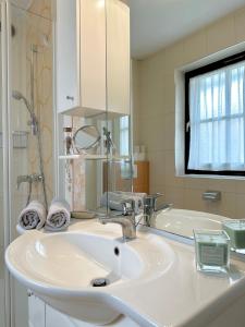een badkamer met een witte wastafel en een bad bij Apartment Butterfly in Čatež ob Savi
