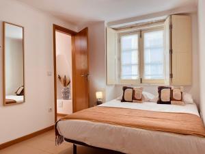 a bedroom with a large bed with a window at Alta apartments in Coimbra