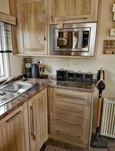 a kitchen with wooden cabinets and a microwave at Glan Hirfaen Where the mountains meet the sea in Porthmadog